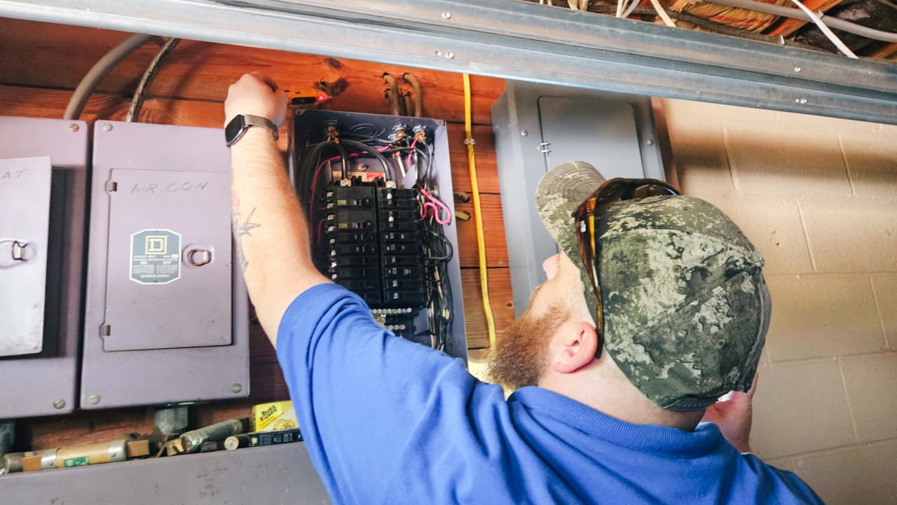 Home inspector examining an interior electrical panel during an annual home maintenance inspection to assess visible components and connections