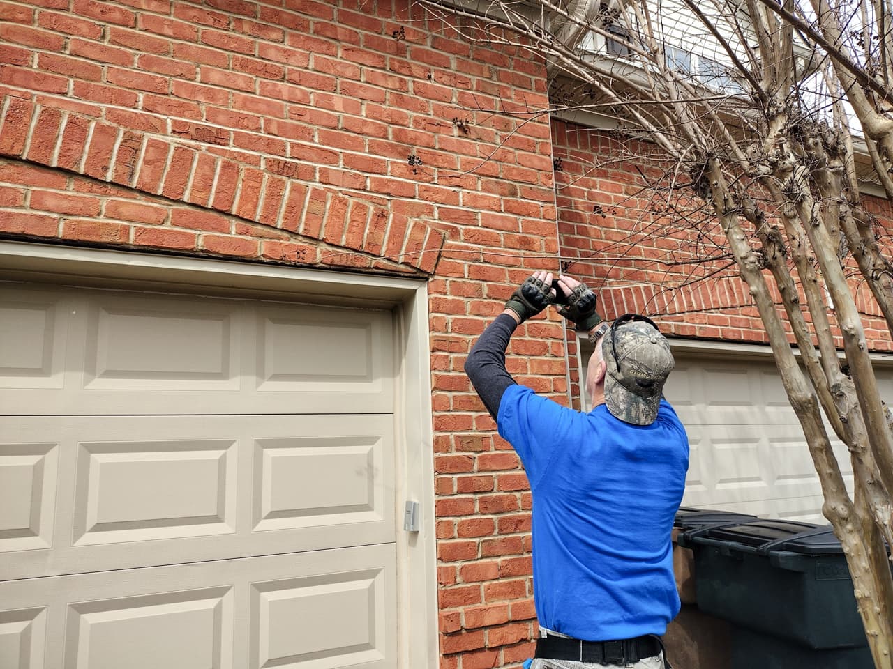 Home inspector examining exterior brickwork near a garage during a seller’s home inspection to identify visible issues before listing
